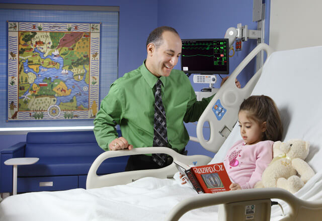 a doctor talks to a little girl in a hospital bed